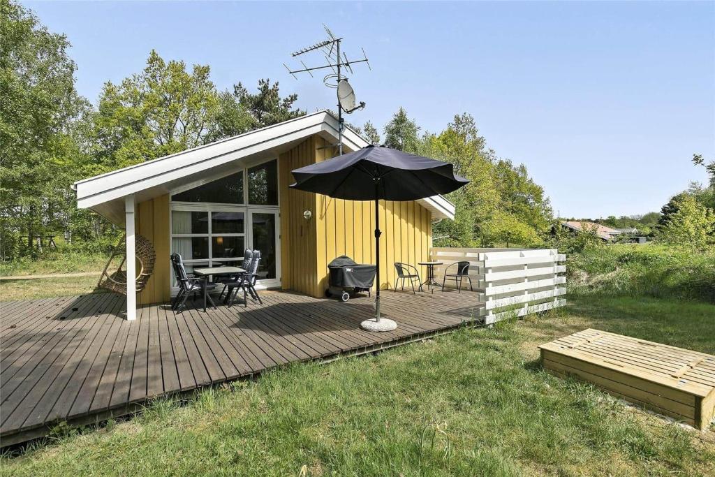 a house with an umbrella on a wooden deck at 1431-Aakirkeby-Strandvangen-13-B in Vester Sømarken