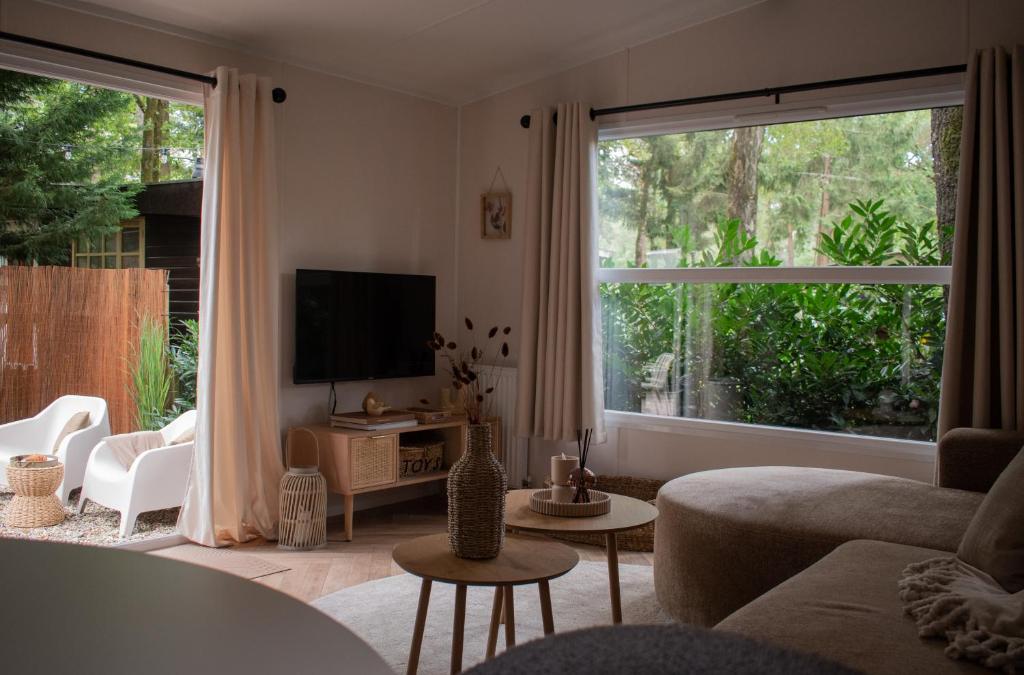 a living room with a couch and a large window at 't Veluws Nest - Knus Chalet Veluwe - Hoenderloo, Honden welkom in Hoenderloo