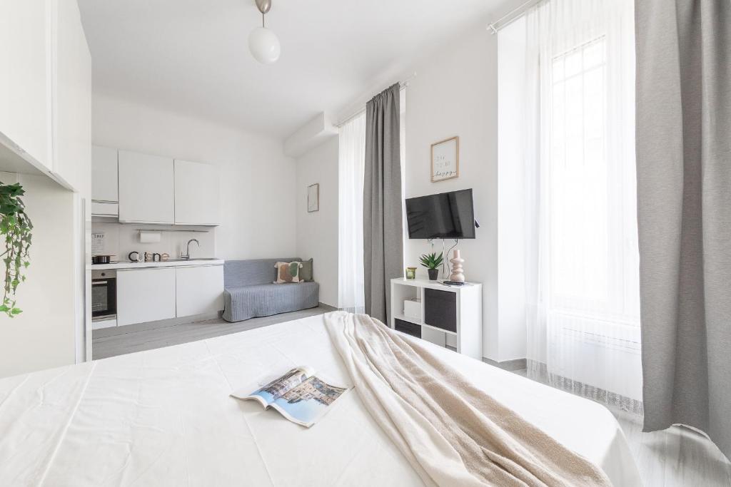 a white bedroom with a bed and a kitchen at Magic Rent - Appartamento Gluck in Milan