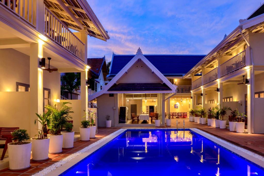 a villa with a swimming pool in front of a house at Viriya Hotel in Luang Prabang