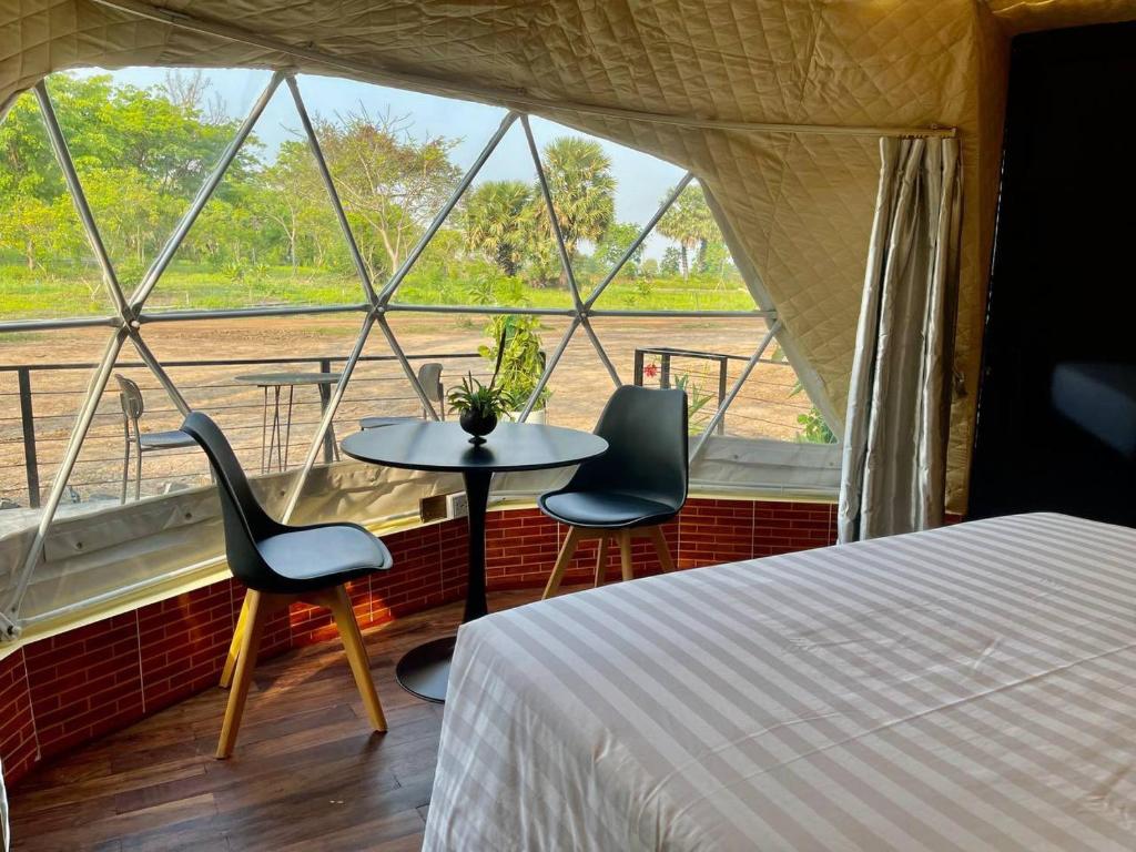 シェムリアップにあるThisak Resort Cheung phnom kulenのベッド1台、椅子2脚、窓が備わる客室です。