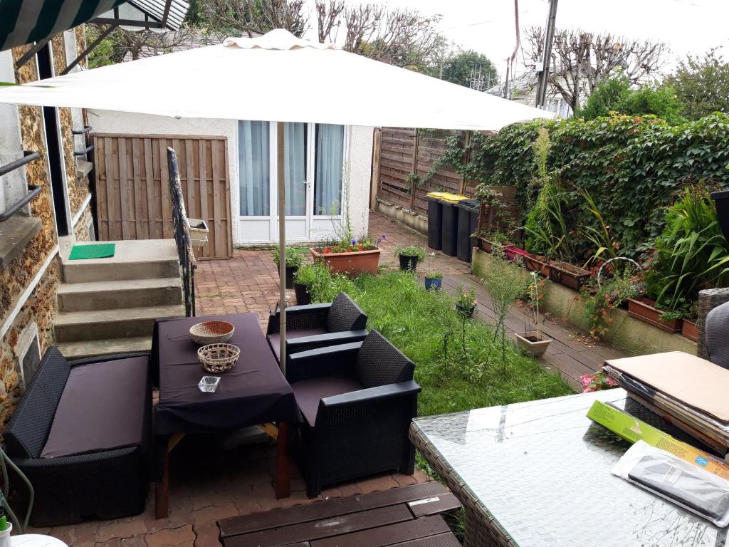 a patio with a table and chairs and an umbrella at Appartement individuel dans charmante maison de ville à la française in Gagny