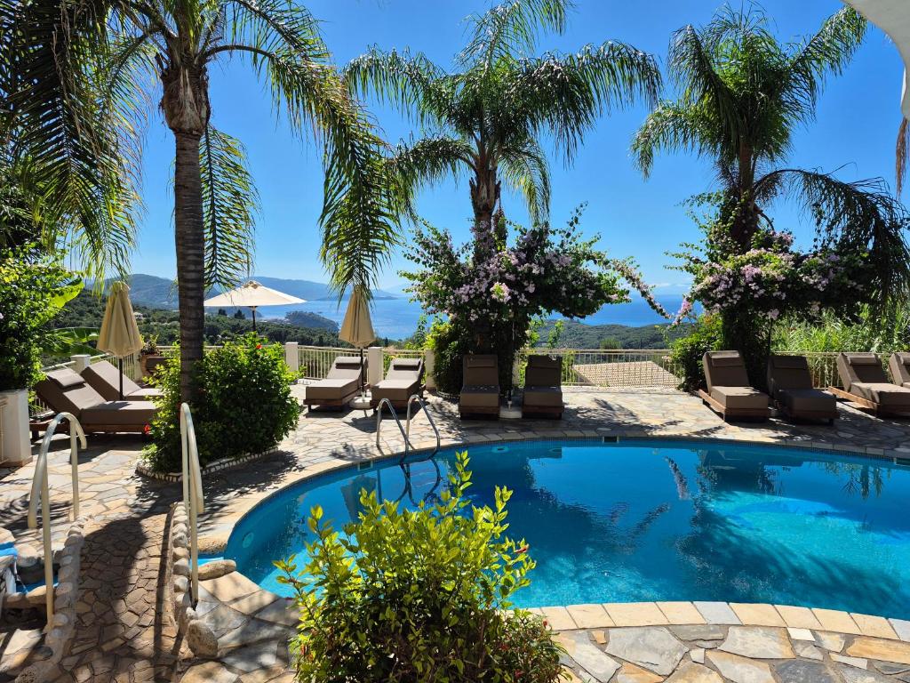 a swimming pool with palm trees and lounge chairs at Filoxenia Sea View in Parga