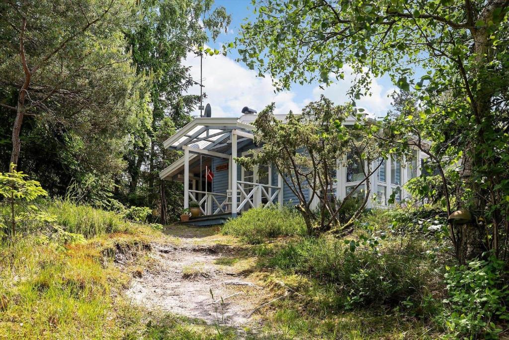 a house in the woods with a dirt road in front of it at 2724-Nexo-Pilegardsvejen-3 in Neksø