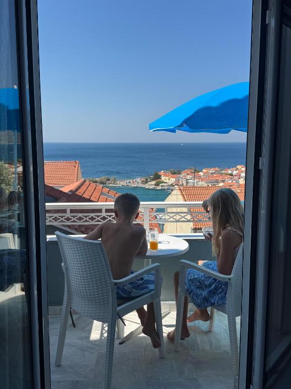 a couple of people sitting at a table on a balcony at Hotel Lenox in Pythagoreio