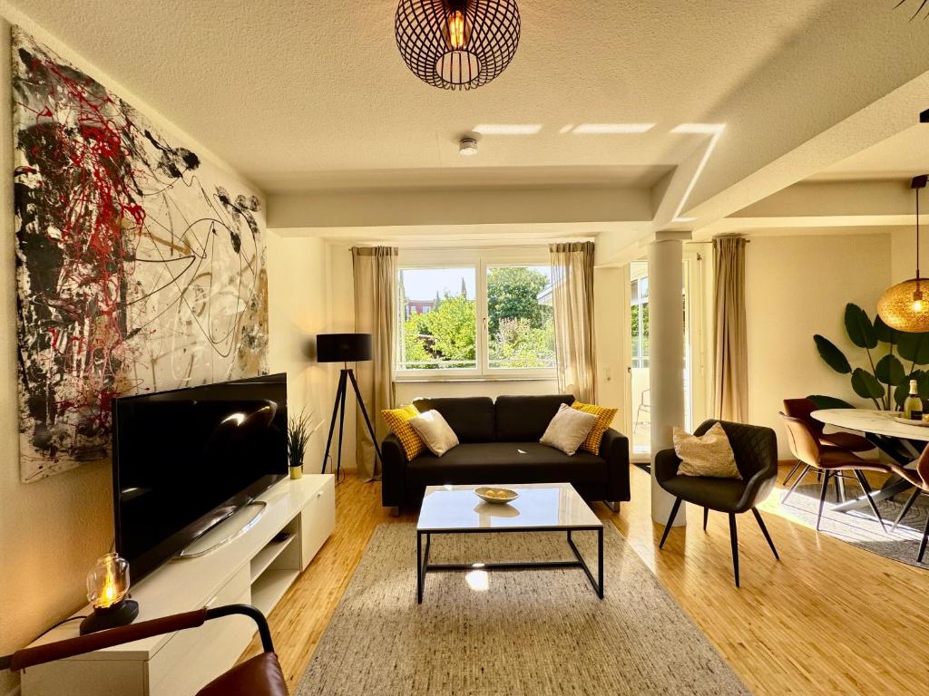 a living room with a couch and a tv at Gartenloft - Design Apartment an der Therme in Bad Krozingen