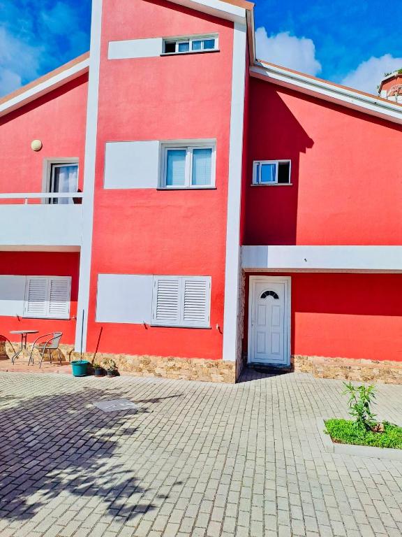 a red and white building with a patio at Brincalquimia in Setúbal