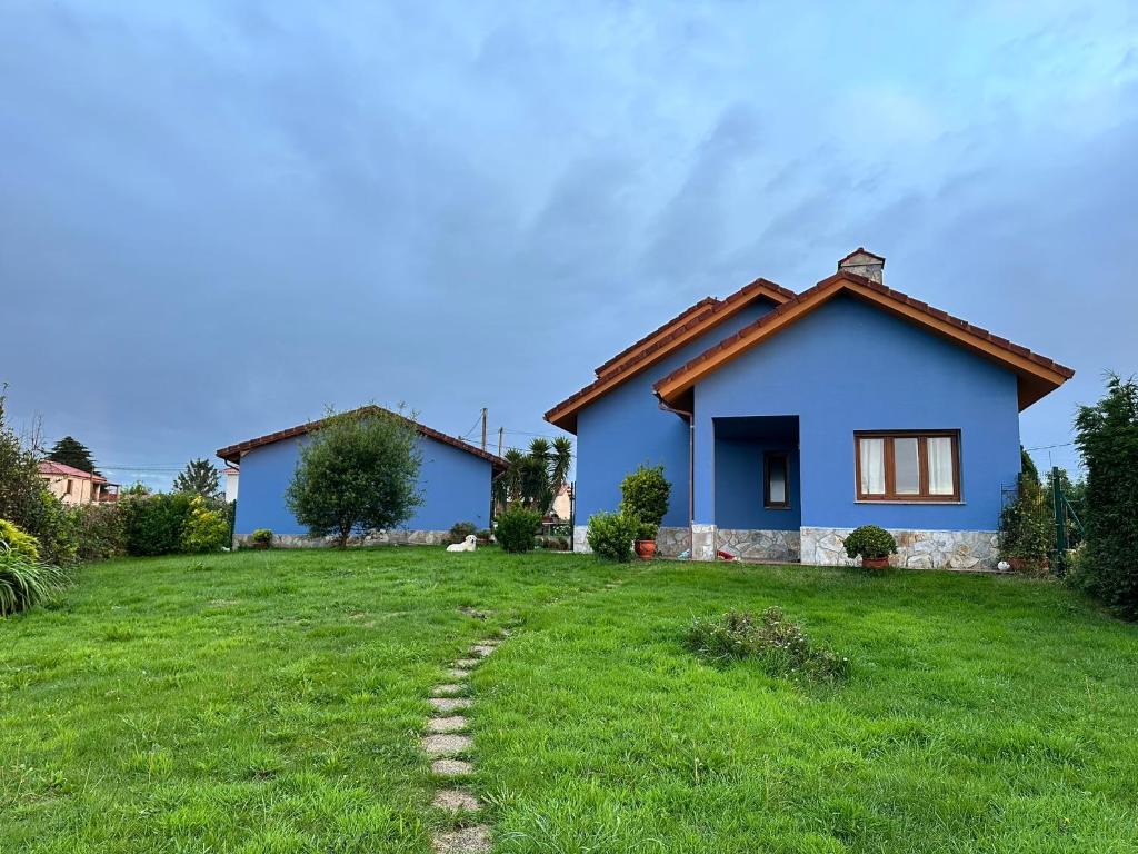a blue house with a green lawn in front of it at Apartamento en Bañugues cerca de Cabo Peñas. in Bañugues