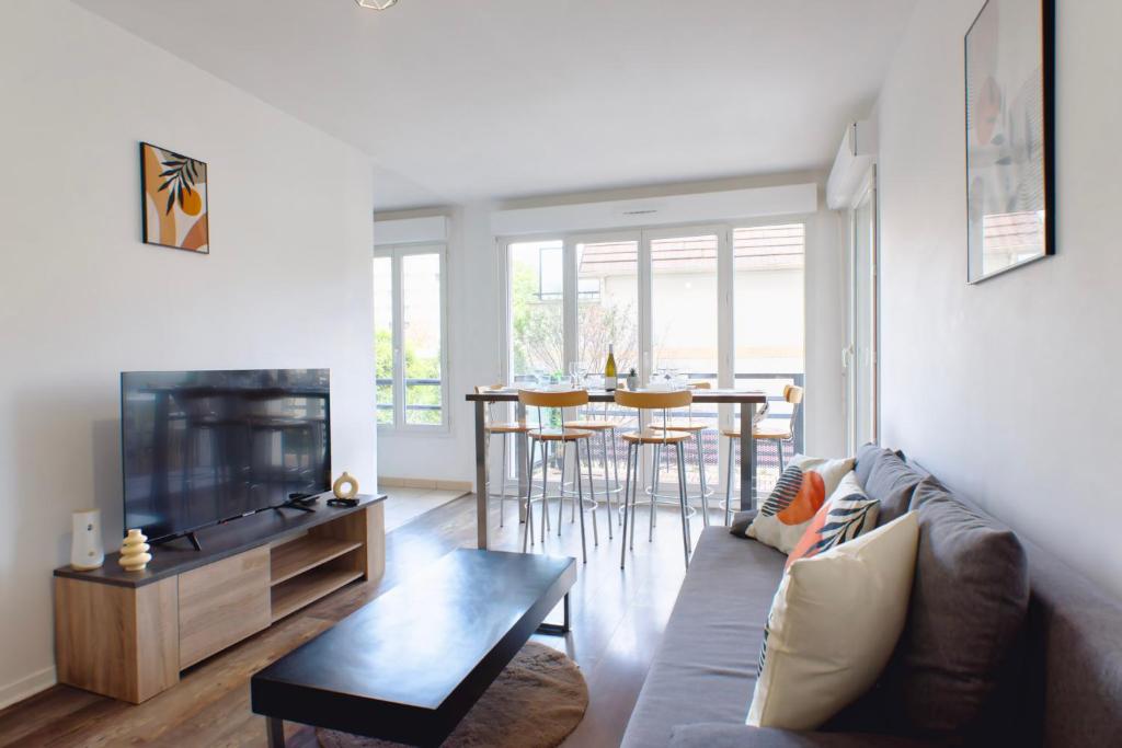 Una sala de estar con un sofá y un televisor. en Appartement cosy parking privé, en Saint-Ouen