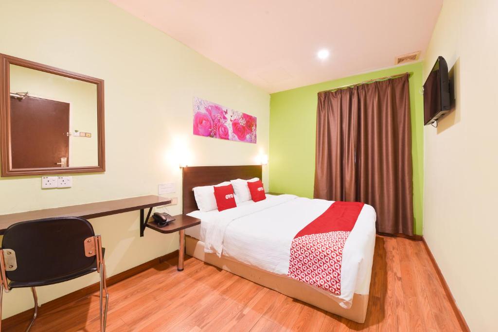 a hotel room with a bed and a desk and a television at Dancenter G Home Hotel in Kota Bharu