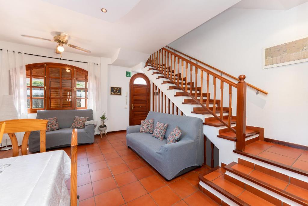 Una sala de estar con dos sofás y una escalera. en Vivelorural Los Tableros Agaete great terrace, en Agaete
