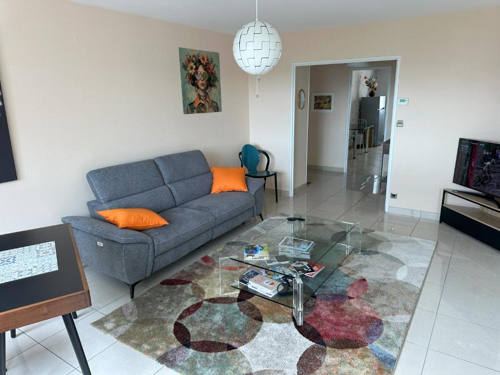 Una sala de estar con un sofá y una mesa de cristal. en Bel appartement spacieux , lumineux, proche Dijon centre auditorium, en Dijon
