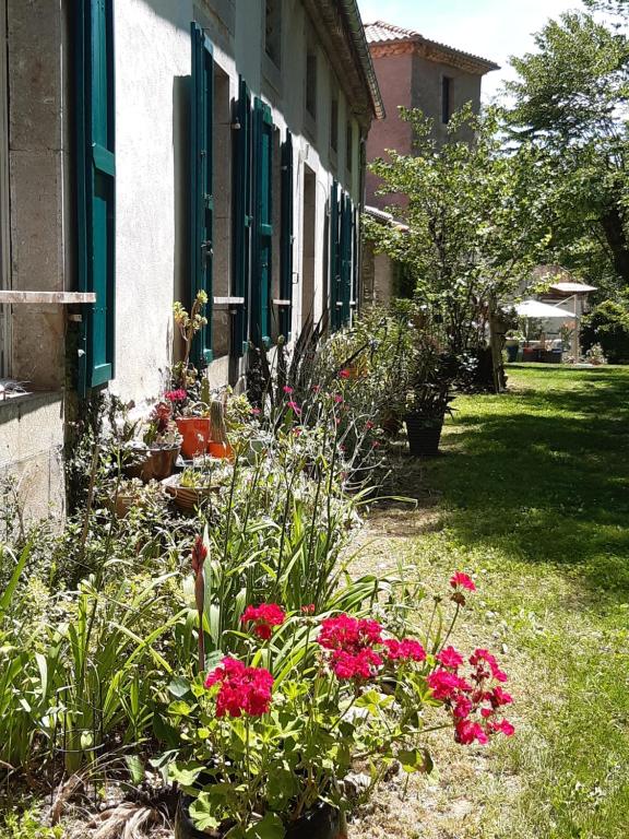 a garden with red flowers in front of a building at Pan Demeure et Granges in Montesquieu-Avantès