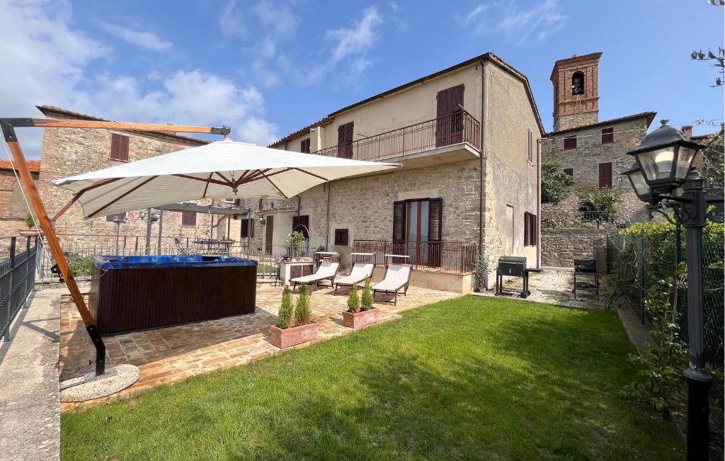 a patio with an umbrella and chairs in a yard at Lovely Apartment In Civitella Benazzone in Civitella Benazzone