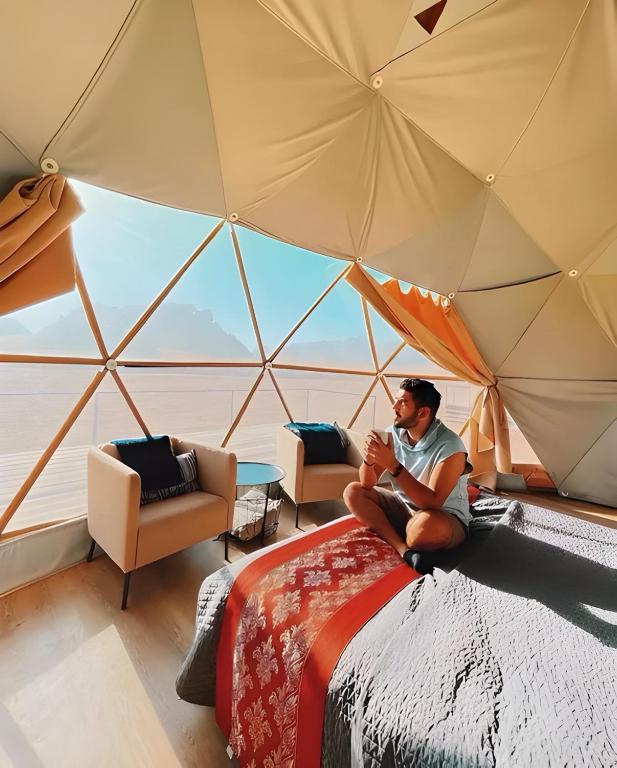 a man sitting in front of a tent at Diamond luxury rum in Wadi Rum