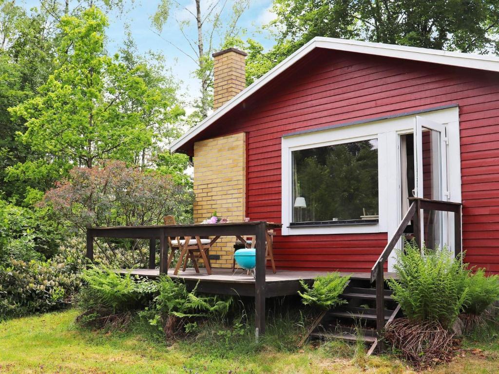 a red house with a deck with a table at 4 person holiday home in Åsljunga in Åsljunga