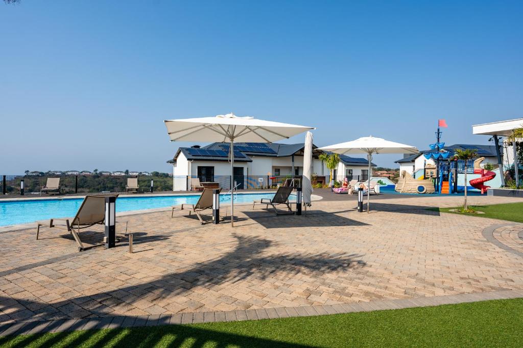 a swimming pool with chairs and umbrellas next to a pool at Ballito Hills 1153 in Ballito