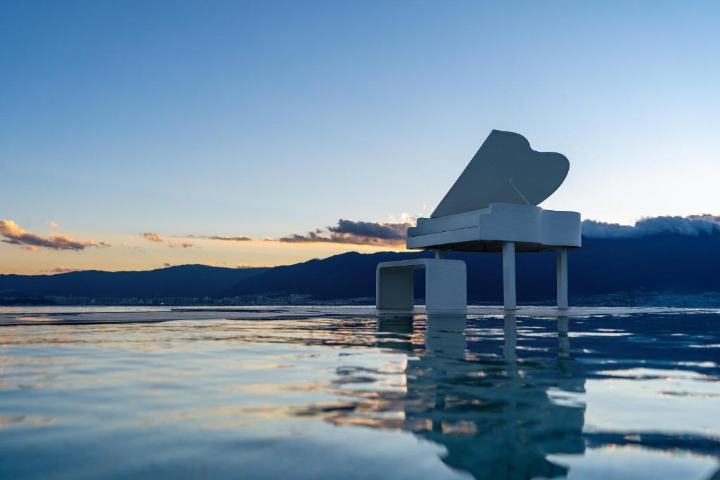 a sculpture sitting on the water with the sunset in the background at Dali Santorini Yuexin Seaview Hotel in Dali Airport