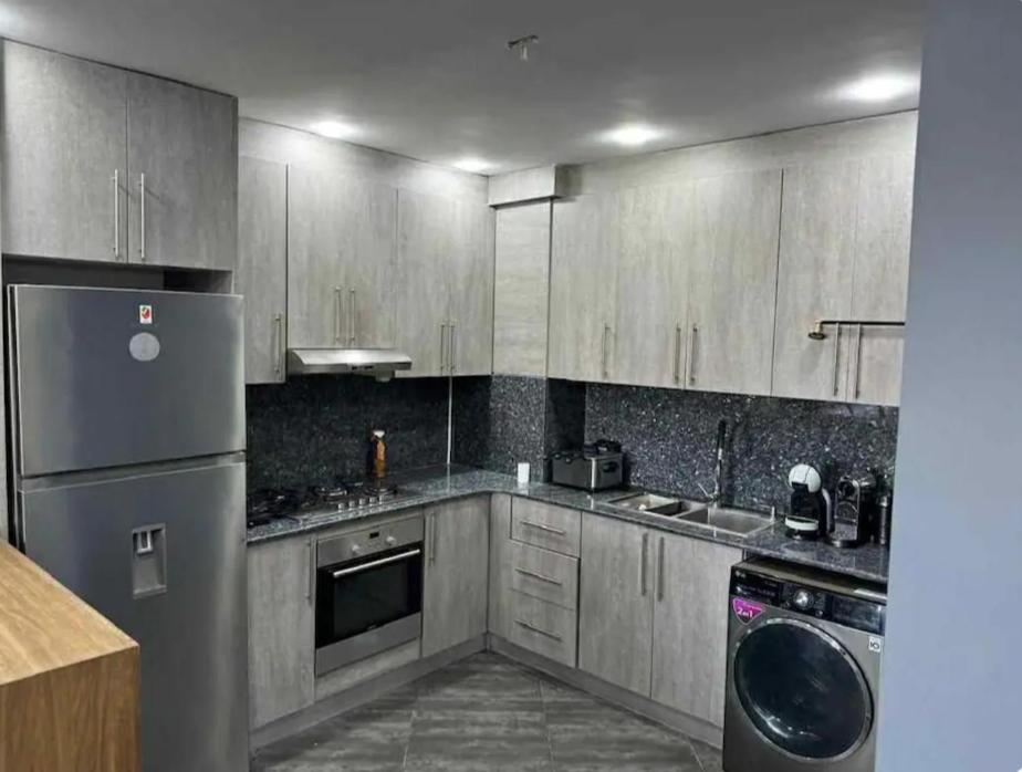 une cuisine avec des appareils en acier inoxydable et des armoires en bois dans l'établissement Logement idéal pour vos séjours - 8ème étage avec ascenseur, à Birmandreis