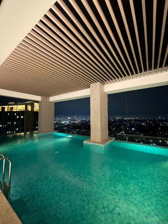 a swimming pool in a building with a city skyline at TranquiLoft LuxLiving in Cilenggang
