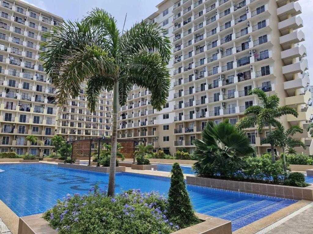 a palm tree in front of a large building at Ocean Breeze Condo in Lapu-Lapu - Private Room with Balcony in Suba