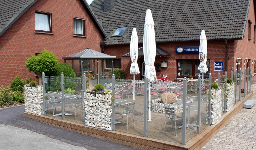 a table with chairs and umbrellas in front of a building at Landgasthaus Veltheimer Hof in Porta Westfalica