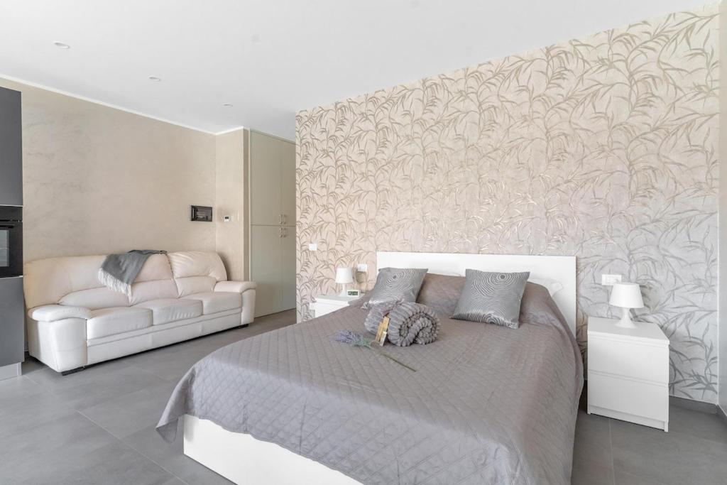 a white bedroom with a bed and a couch at Aura Suite near Lake Garda in Castiglione delle Stiviere