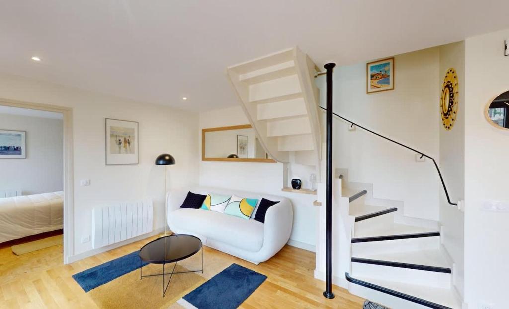 a living room with a staircase and a white couch at Au bord de l'Odon in Louvigny
