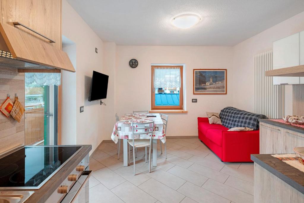 a living room with a red couch and a table at Appartamento Nuovo A San Giovanni in Pozza di Fassa