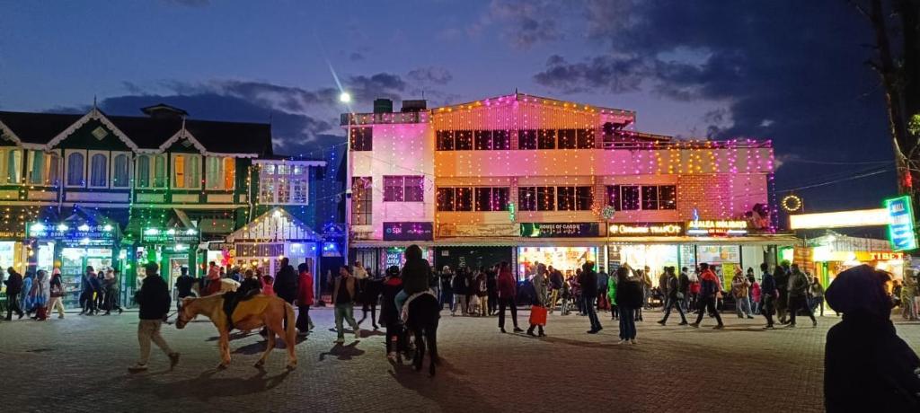 a group of people walking around a city at night at Azalea Holidays On Mall in Darjeeling