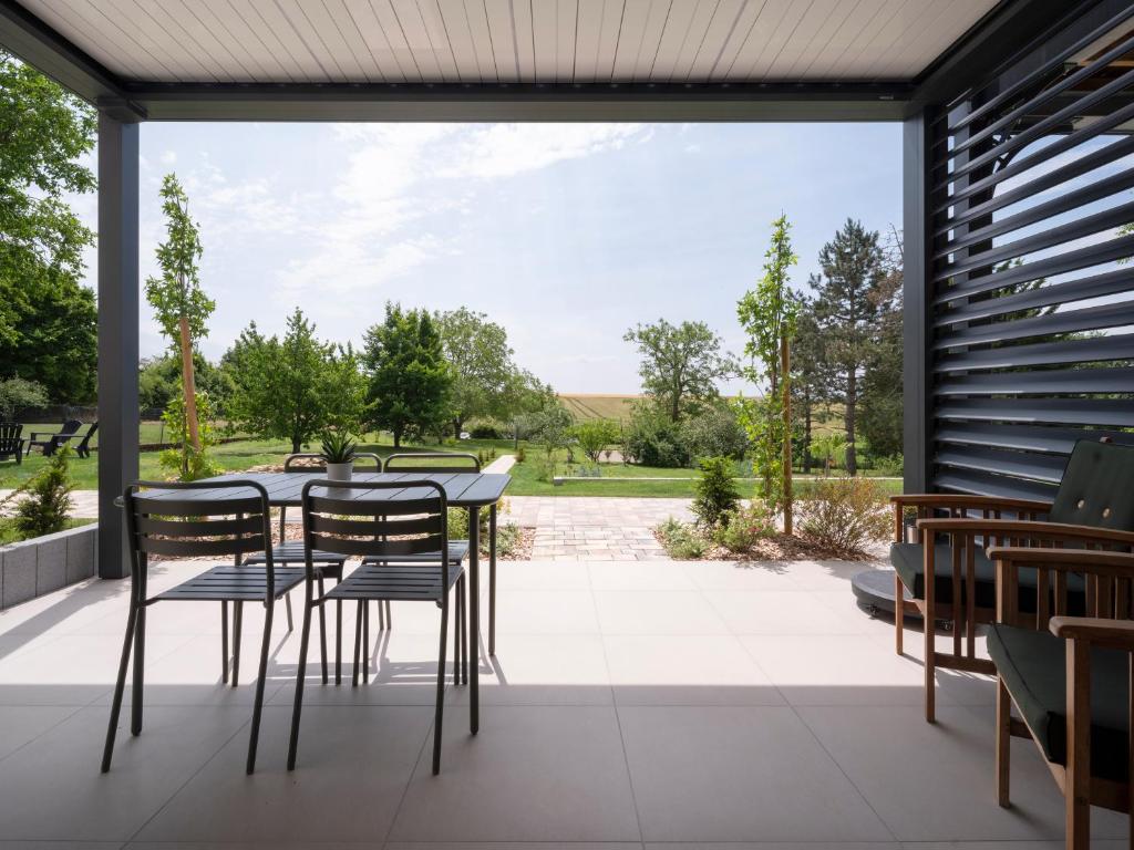 a patio with a table and chairs looking out onto a garden at La Ferme d'Estelle in Vulmont