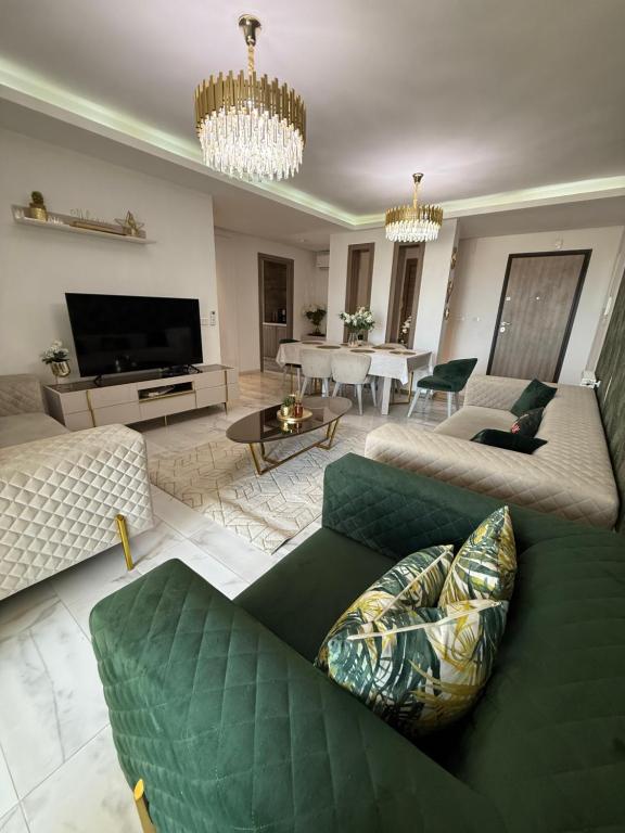 a living room with a green couch and a television at Élégant appartement avec parking privé proche aéroport et centre ville Tunis Laouina in El Aouina