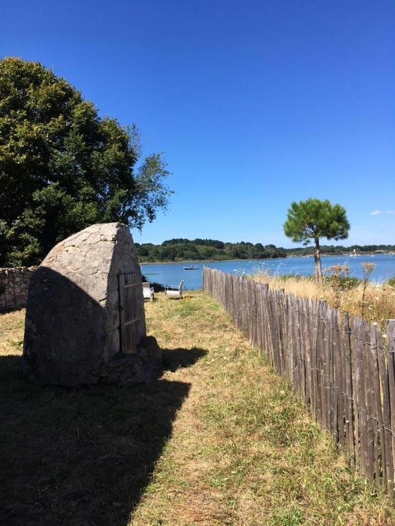 a stoneolith next to a fence and a body of water at Maison face à la mer in Sarzeau