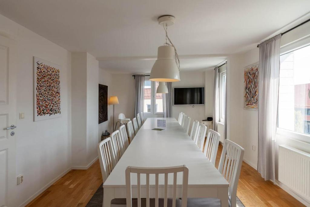 a white dining room with a long table and chairs at Ferienhaus Malte in Braunlage