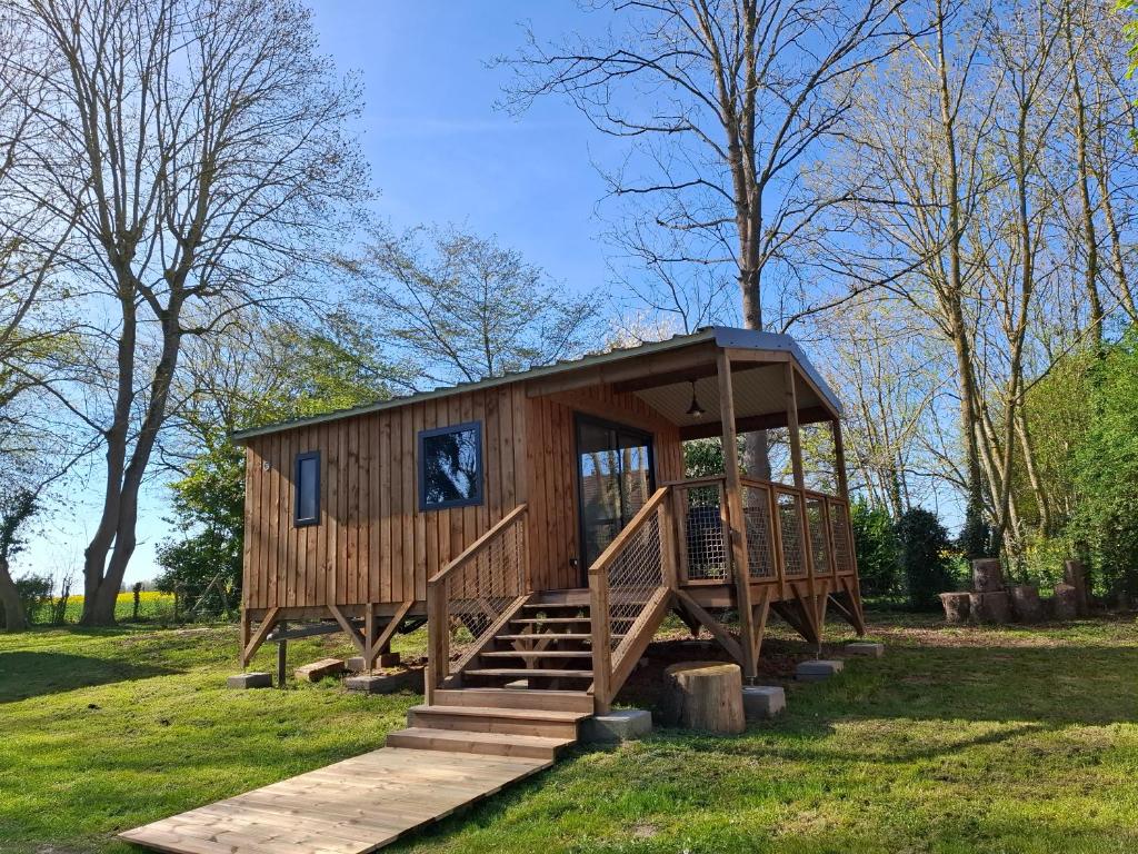a wooden cabin in a field with stairs and trees at Les Cabanes d'Isa - Cab'Fer in Flexanville