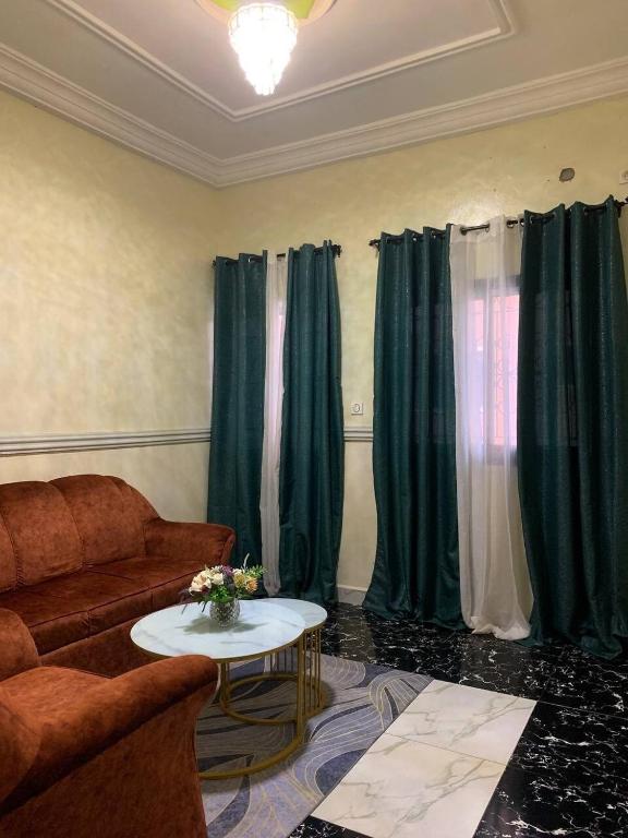 a living room with a couch and green curtains at Air-conditioned apartment, secured Residence Kribi in Kribi