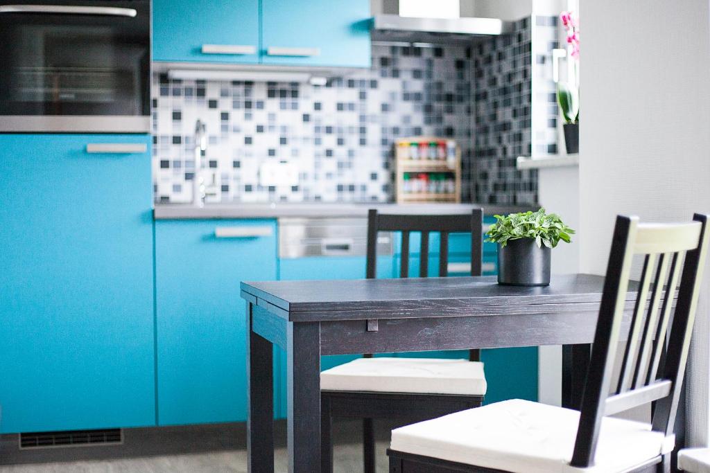 une cuisine avec des armoires bleues et une table avec une plante en pot dans l'établissement Hoofer Apartments, à Schauenburg