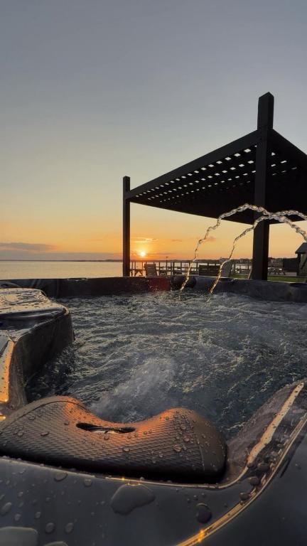 a hot tub with an umbrella and the ocean at Private beach on a fenced in property sunset views in Hampton Bays