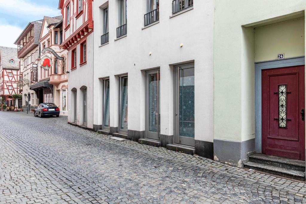 a cobblestone street with buildings and a red door at Bacchus Holiday Homes in Bacharach