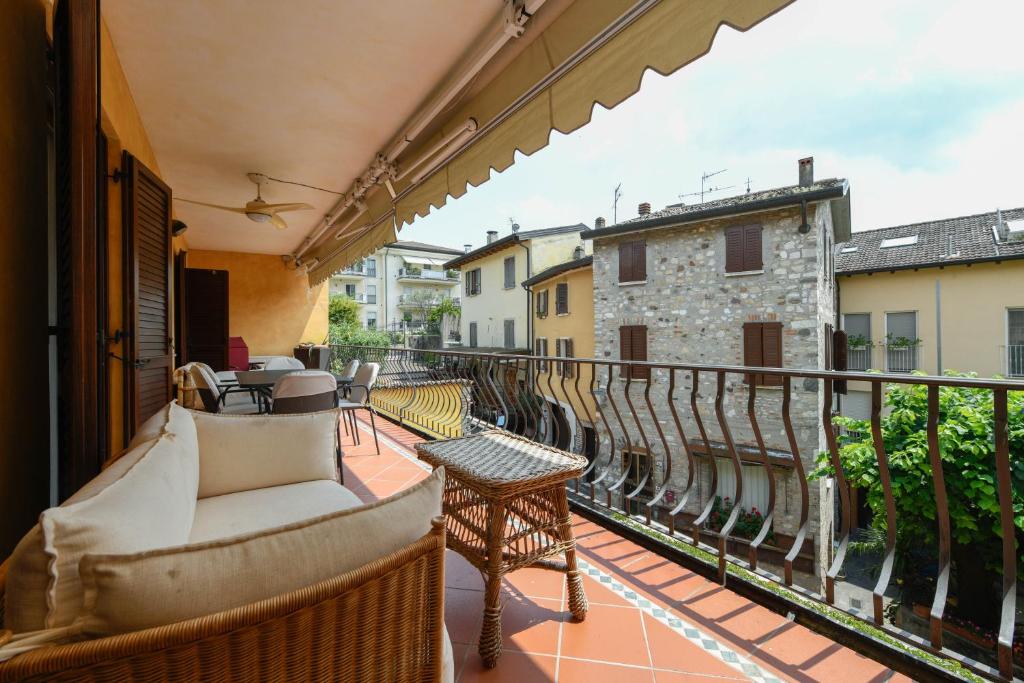 a balcony with a couch and chairs on a balcony at Prestige Apartment in Sirmione