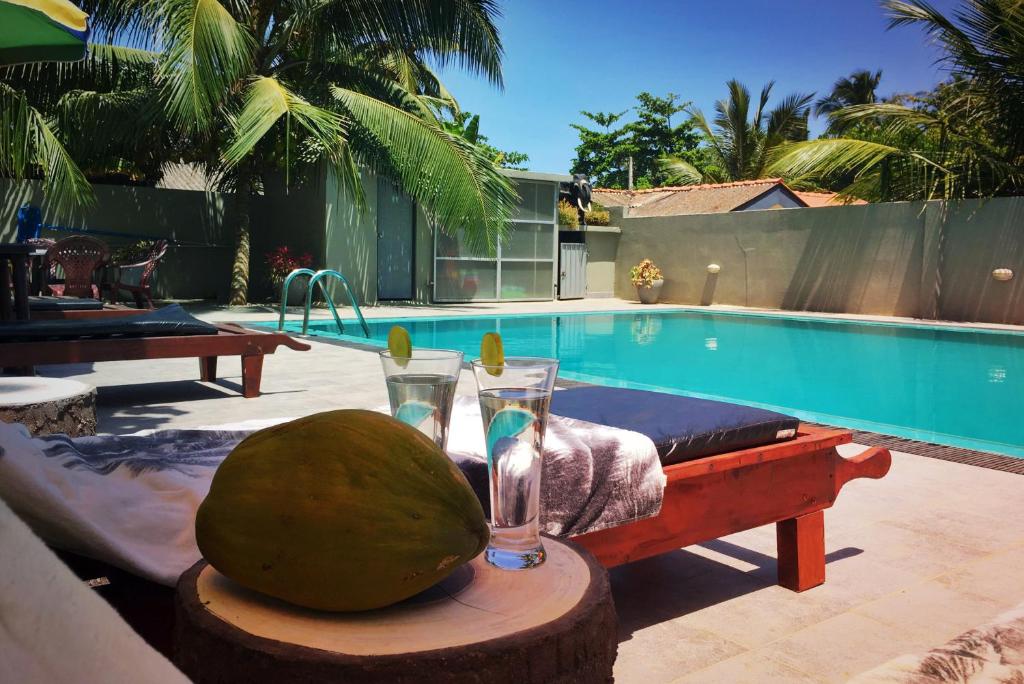 a pool with a table with two glasses and a melon at Karl Holiday Bungalow in Kalutara