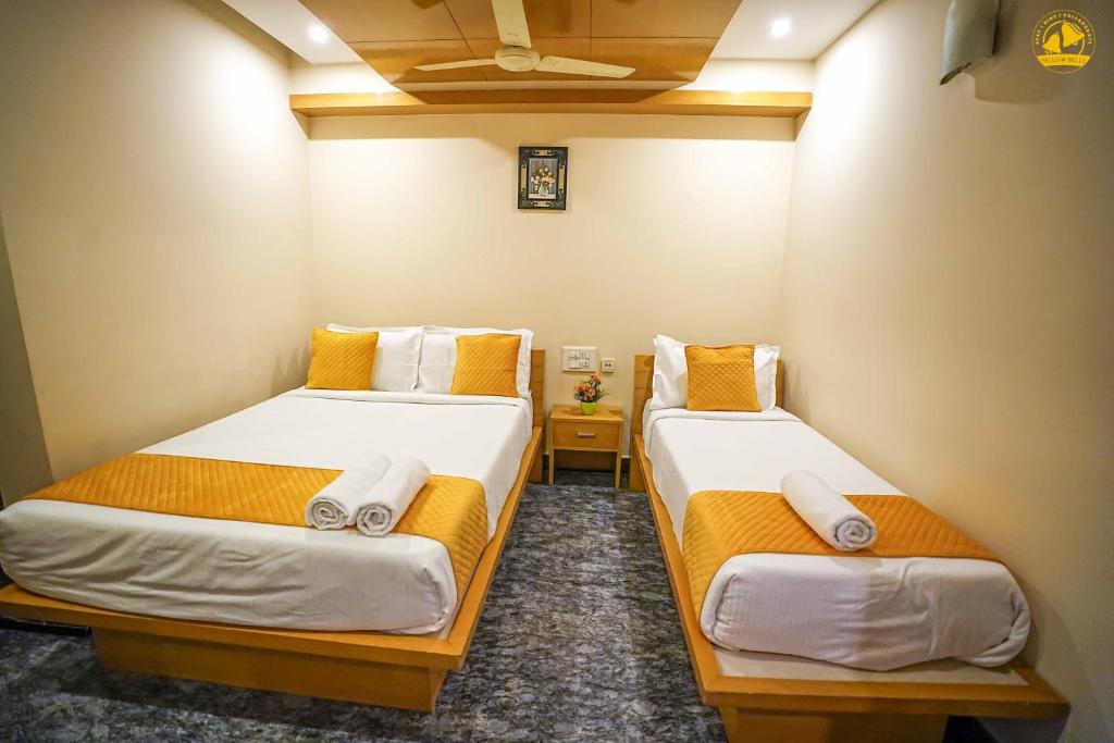 een kamer met 2 bedden met oranje en witte lakens bij Hotel Liv By Yellow Bells in Hyderabad