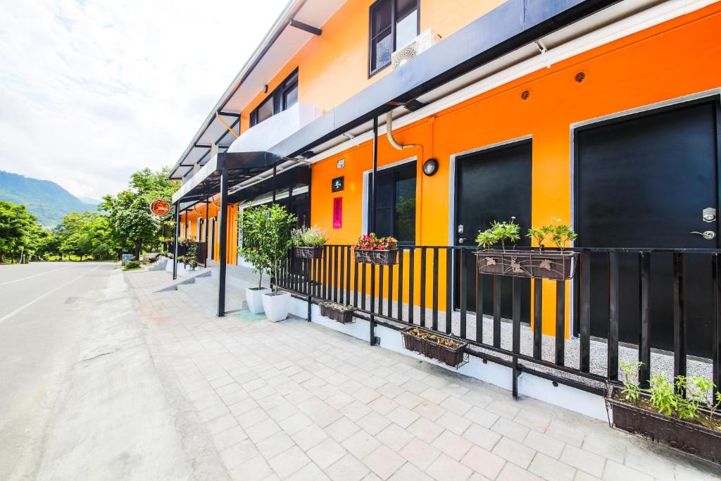 溫泉村的住宿－風行館民宿，橙色和黑色的建筑,窗户上装有盆栽植物