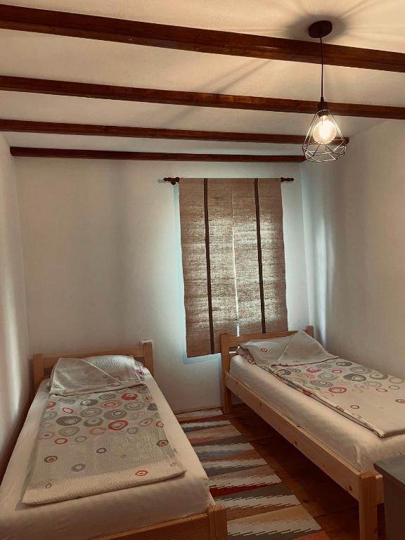 two twin beds in a room with a window at Dobál Vendégház in Lunca de Sus
