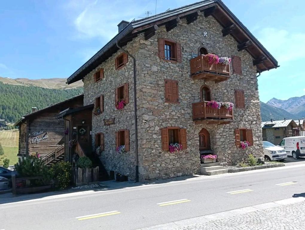 een stenen gebouw met bloembakken op de ramen bij PiZABELA MANSARDE in Livigno