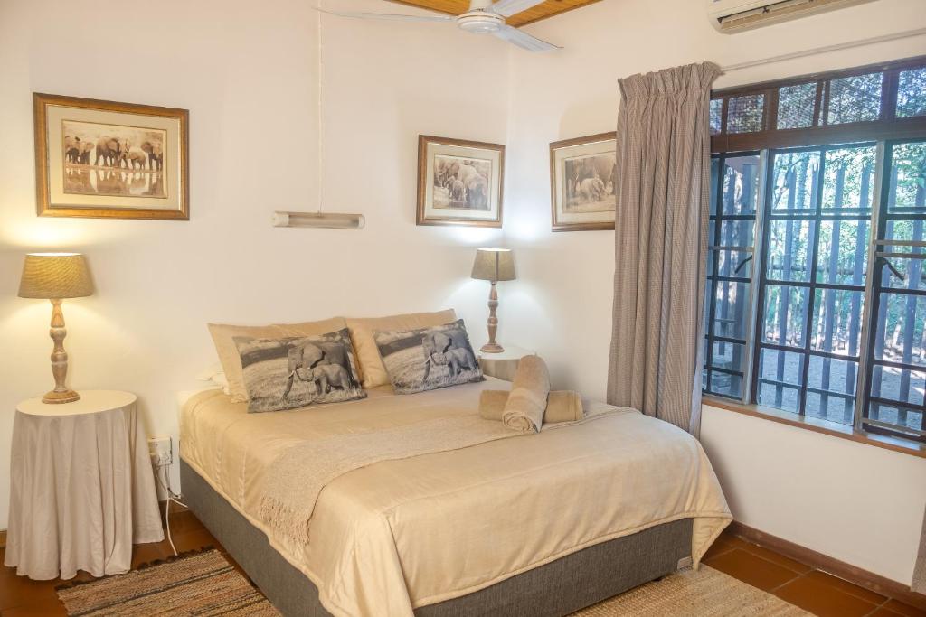 ein Schlafzimmer mit einem Bett und einem großen Fenster in der Unterkunft Owl House Marloth Park in Marloth Park