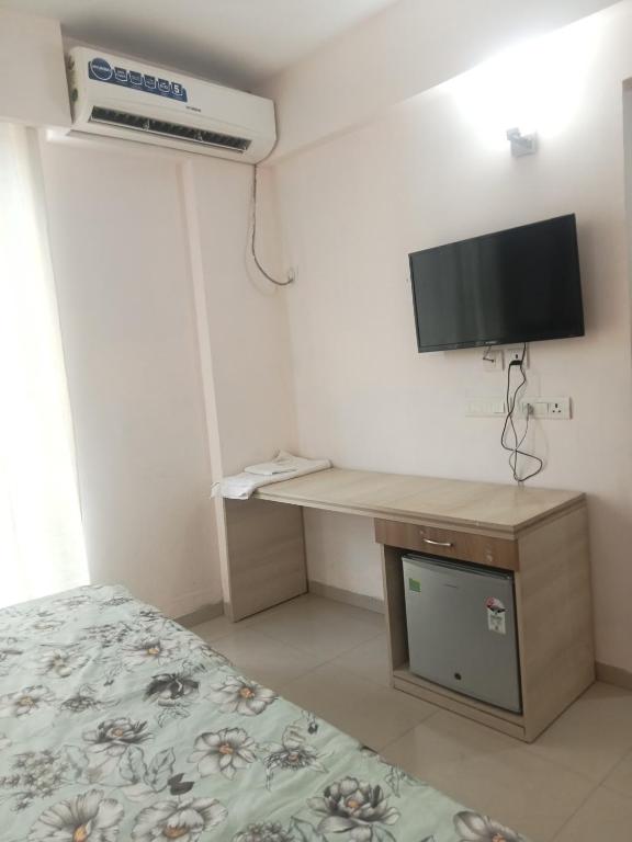 a bedroom with a bed and a desk with a television at Vrindavan Omex in Vrindāvan