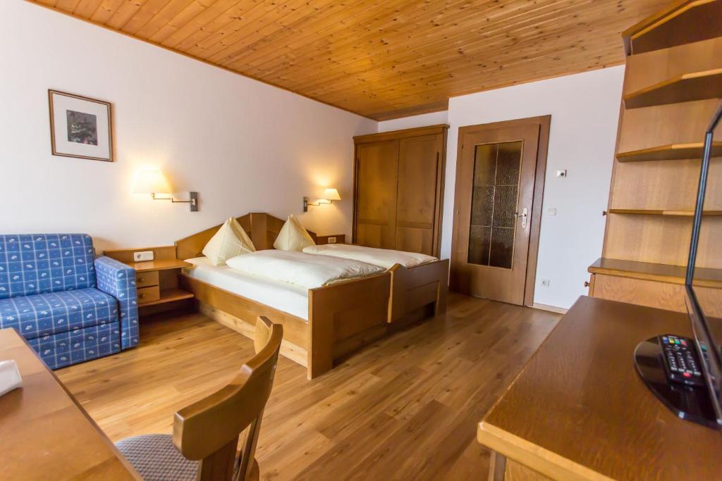 a hotel room with a bed and a blue couch at Haus Bergland in Bad Kleinkirchheim