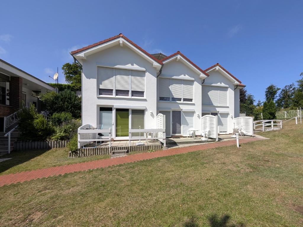 a white house with white chairs and a yard at Appartements Am Selliner Hochufer - wenige Gehminuten zum Strand in Ostseebad Sellin