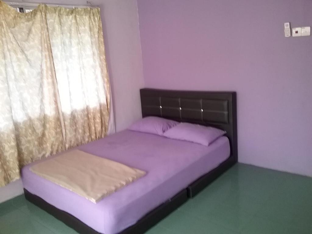 um quarto com uma cama com lençóis roxos e uma janela em Apple Boutique Homestay em Kuantan